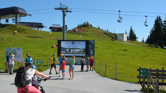LED video wall below the Fleckalmbahn mountain station with commercial for the Danube Private University