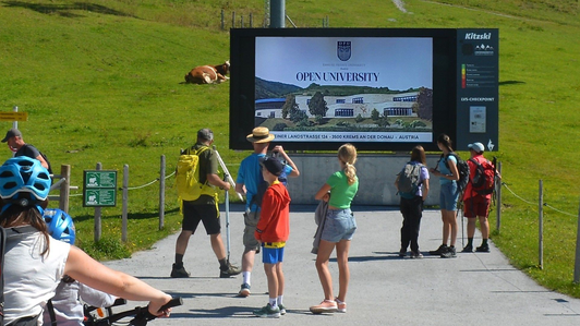 LED Videowall mit Werbespot der Private University St. Gilgen an der Bergstation der Fleckalmbahn im Wandergebiet KitzSki, Kitzbühel